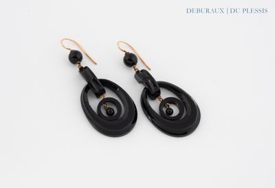 a pair of black and gold earrings on a white surface
