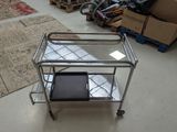 a metal cart with a glass top on the floor in a room