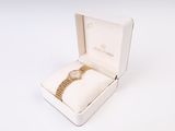 une boîte blanche contenant une montre, posée sur une surface blanche