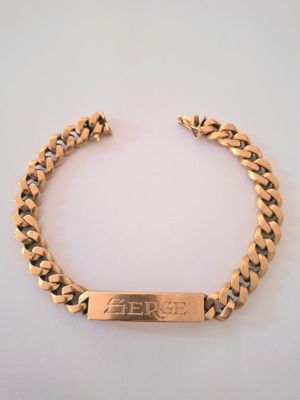 a close up of a gold bracelet on a white surface