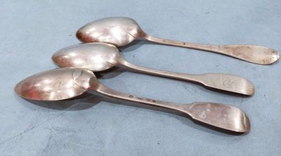 three silver spoons sitting on top of a table next to each other