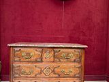 une commode en bois dans une pièce où est accroché un tableau au mur