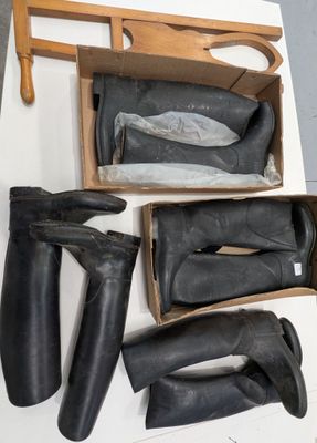 Plusieurs paires de bottes noires se trouvent dans une boîte posée sur une table
