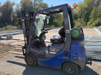 a blue fork truck that is parked on the side of the road