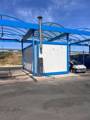 une photo d'un bâtiment bleu et blanc devant lequel est garée une voiture
