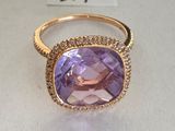 a close up of a ring with a purple stone surrounded by diamonds