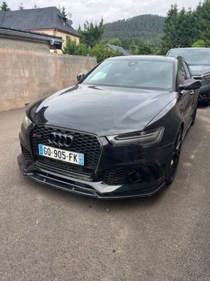 L'Audi noire est garée sur un parking, près d'un mur.