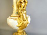 a gold and white vase with a statue on it