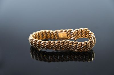 a close up of a gold rope bracelet on a black surface