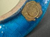 a blue vase with a gold medallion on it
