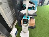 deux robots aspirateurs posés sur la pelouse devant un immeuble