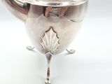 an antique silver teapot with a decorative design on a stand