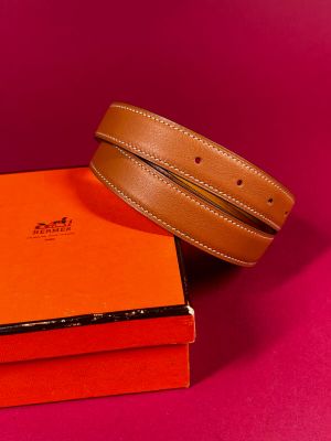 two belts and a box on a pink surface