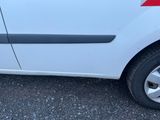 une petite voiture blanche avec une bande rouge, garée sur un parking