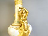 a gold and white vase with a woman on it