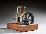 une petite maquette de machine à vapeur posée sur un socle en bois