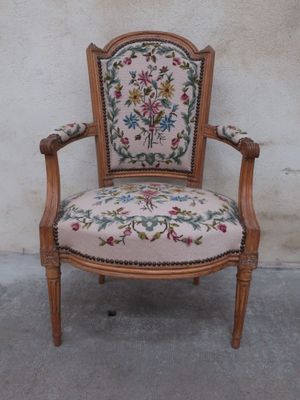 an old chair with a floral upholstered back and arms
