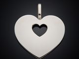 a silver heart shaped pendant with a hole in the middle