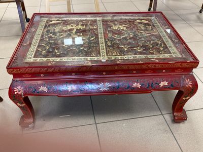 une table rouge avec un plateau en verre posée sur un sol carrelé