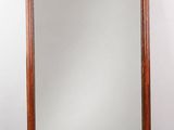 un grand miroir en bois orné d'un motif décoratif dans sa partie supérieure