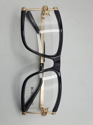 une paire de lunettes noires et dorées accrochée à un mur blanc
