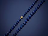 a close up of a blue beaded necklace with a gold clasp