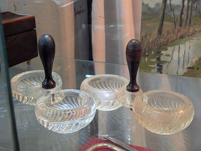 une vitrine en verre sur laquelle sont posés trois cendriers en verre