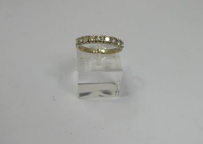 a yellow gold ring with diamonds on top of a clear acrylic block
