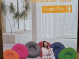 packaging of inflatable sofa in a store with a woman sitting on the floor