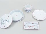 a white table with a bowl, plate, bowl, and cup on it