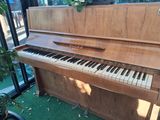 a piano that is sitting in a room by a window