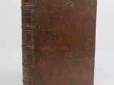 an old brown book sitting on top of a table next to a white wall