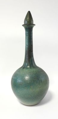 un vase vert posé sur une surface blanche