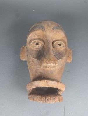 une sculpture en argile représentant le visage d'un homme, accrochée au mur