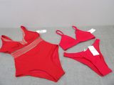 two pieces of red swimsuits on a bed with a price tag