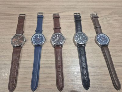 Quatre montres différentes sont alignées sur une table en bois