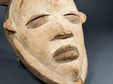 a close up of a wooden mask on a gray surface