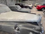 many old cars parked in a garage with a red car in the background