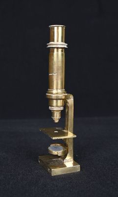 un gros plan d'un microscope doré sur fond noir