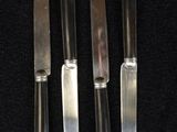 four knives are lined up on a black surface with a black background