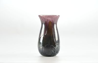 un vase violet posé sur une table, sur fond blanc