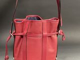 pink leather purse with zippers and handles on a gray background