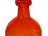 an orange glass vase with a red top on a white background