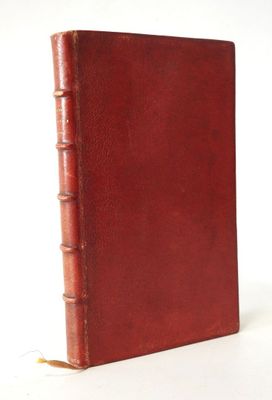 un vieux livre à la couverture rouge posé sur une surface blanche