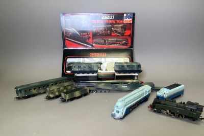 Plusieurs petits trains sont alignés sur une table, à côté d'une boîte