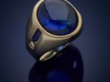a close up of a gold ring with a blue stone