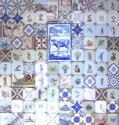 un mur recouvert de carreaux bleus et blancs sur lesquels sont représentées des images