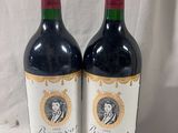 two bottles of red wine sitting next to each other on a table