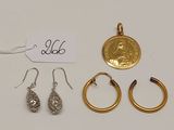 trois paires de boucles d'oreilles et une pièce d'or posées sur une surface blanche