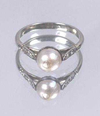 two rings with pearls and diamonds on them on a white surface
